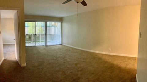 the living room of an empty house with a ceiling fan